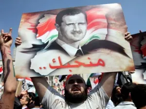 متظاهر مؤيد للاسد يحمل صورته خلال تظاهرة في دمشق