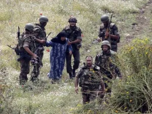 جنود سوريون يسلمون سيدة سورية مسنة الى الجيش اللبناني بعد محاولتها العبور الى شمال لبنان من منطقة العريضة السورية لملاقاة عائلتها
