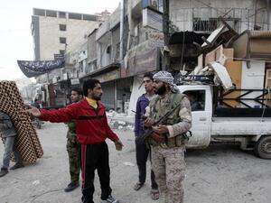 رجل يتحدث مع مسلح من القات الموالية للاسد فيما يقوم رجل اخر بنهب اثاث منزل في بلدة الحجيرة التي سيطرت عليها هذه القوات من المعارضة قرب دمشق
