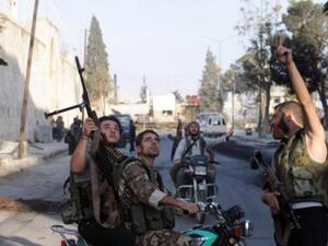 مقاتلون من المعارضة السورية يراقبون مروحية تابعة لقوات النظام تحلق فوق معرة النعمان