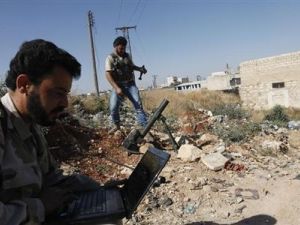 مقاتل من الجيش السوري الحر المعارض يستخدم كمبيوتر محمول واخر يستعد لاطلاق قذيفة مورتر قرب مطار عسكري تسخدمه قوات الرئيس السوري بشار الاسد في حلب
