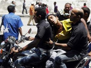 مصريان يحملان على دراجة نارية شابا أصيب بقنبلة غاز مسيل للدموع أثناء مواجهات مع الشرطة امام وزارة الداخلية 
