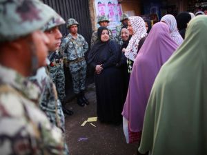 Women standing near The Citadel wait in line to vote watched by soldiers. Women standing near The Citadel wait in line to vote watched by soldiers.