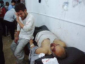 رجل يبكي بجوار جثة رجل اخر قتلته القوات السورية في حمص