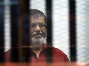 Egypt's ousted Islamist president Mohamed Morsi, wearing a red uniform, stands behind the bars during his trial in Cairo on June 21, 2015. (AFP/File)