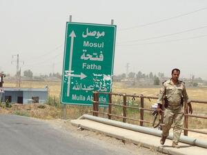 An Iraqi soldier walks past a sign pointing toward Mosul. (AFP/File)