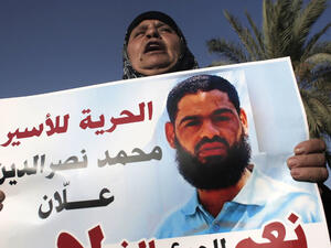 The mother of Muhammad Allan holds a sign calling for his release. (AFP/File)