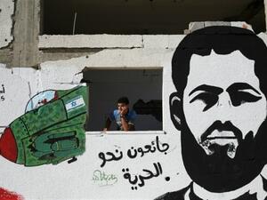 A young Palestinian stands next to a graffiti portrait of Muhammad Allan, who was rearrested following a hunger strike that lasted longer than two months. (AFP/File)