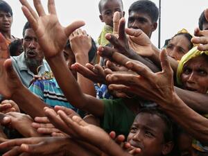 Rohingya refugees reaching for food aid at a refugee camp in Ukhiya near the Bangladesh-Myanmar border (AFP/File Photo)	