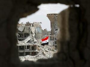 العلم السوري وسط الحطام عند مدخل حي الحجر الأسود عند الأطراف الجنوبية لدمشق
