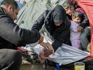 لاجئة سورية تحمم رضيعتها في ظل ظروف جوية قاسية