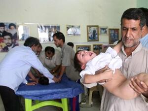 عراقي يحمل طفلا مصاب 