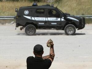 متظاهر فلسطيني يحمل حجارة في مواجهة دورية اسرائيلية
