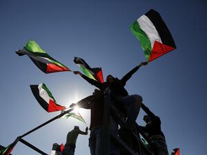 Palestinians wave flags during a demonstration in the West Bank. (AFP/File)