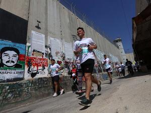  Participants in the Palestine Marathon running along the Israeli apartheid wall surrounding the biblical city of Bethlehem. (Photo: WAFA Images / Ahmad Mizher)