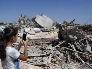 A Palestinian girl photographs the rubble of a home demolished by the IDF on July 26, 2016. (AFP/Ahmad Gharabli)
