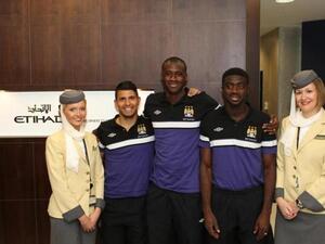 Manchester City Football Club team members Sergio Aquero, Yaya Toure and Kolo Toure flanked by Etihad Airways Business Class Lounge attendants at Manchester Airport before boarding their flight to Beijing