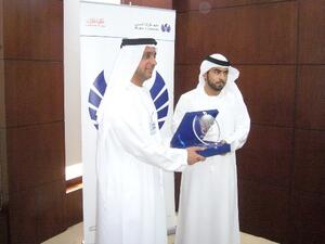 أحمد عبدالله بن لاحج يتسلم درع تذكاري من  راشد الفلاسي مدير المشاريع الخيرية بجمعية دبي الخيرية