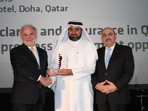 المهندس جاسم تلفت، المدير التنفيذي للمجموعة في الإدارة العامة للمشاريع الرئيسية والإدارة العامة للمرافق في مؤسسة قطر (وسط) يتسلم الجائزة من قبل السيد إدموند اوسوليفان، رئيس مجلس إدارة ميد (يسار) بحضور السيد جبرا رجا غندور، المدير التنفيذي لبنك قطر الدولي
