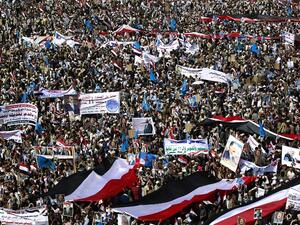 Yemenis wave national flags and hold placards during a protest against the Saudi-led coalition, commemorating one year of the alliance's military campaign against insurgents on March 26, 2016 next to the Monument to the Unknown Soldier in the Yemeni capital Sanaa. (AFP/Mohammed Huwais)