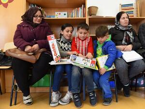 Refugee children and their parents from Afghanistan look at books and games in the refugee camp "Bayernkaserne" in Munich, southern Germany, on March 21, 2016. (AFP/Christof Stache)