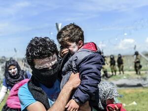 A family with toothpaste smeared over their faces as a protection against teargas, moves to safety as refugees and migrants clash with Macedonian police during a protest to reopen the border near their makeshift camp in the northern Greek border village of Idomeni, on April 10, 2016. (AFP/Bulent Kilic)
