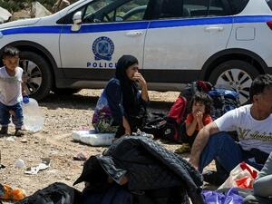 Refugees and migrants wait by a police car in Crete, after being rescued from another capsized vessel on May 31. (AFP/Stringer)