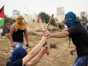 Palestinians prepare to launch a rock from a homemade slingshot during clashes with Israeli soldiers. (AFP/FIle)