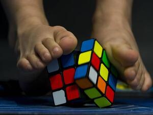 A young competitor tries to solve a Rubik's cube using the feet during the Rubik's Cube World Championship in Sao Paulo, Brazil. (AFP/ File Photo)