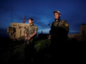 مقاتلون أكراد من وحدات حماية الشعب يقفون بجوار مركبة عسكرية أمريكية في بلدة الدرباسية السورية على الحدود مع تركيا
