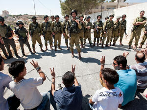 Palestinians in chains symbolizing solidarity with prisoners in Israeli jails face soldiers during a protest in Al Ma'sara, West Bank. (Shutterstock/ File)