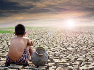 Sad boy sitting on dry ground and sunset . (Shutterstock/ File Photo)