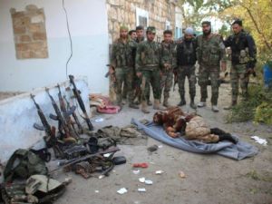 جنود من الجيش السوري يقفون امام جثة مقاتل اسلامي
