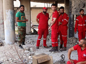 Members of the Red Crescent and a Syrian army soldier gather at the entrance of a damaged building in the government-controlled part of the besieged town of Daraya. (AFP/File)