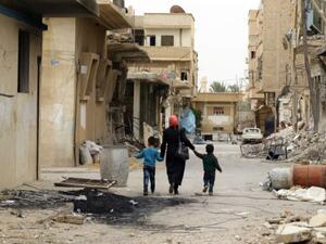 امراة وطفلاها يسيرون في شارع بمدينة تدمر السورية