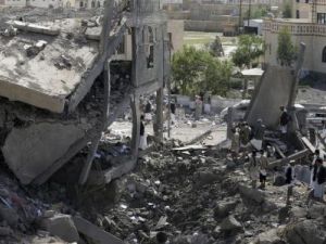 متشددون حوثيون يقفون على أنقاض مبنى دمر في غارة جوية بمدينة عمران

