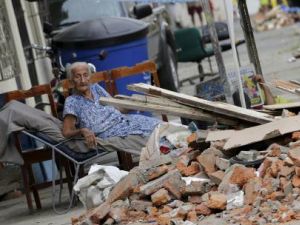 امرأة تجلس خارج منزلها المدمر بفعل الزلزال في الإكوادور يوم الجمعة
