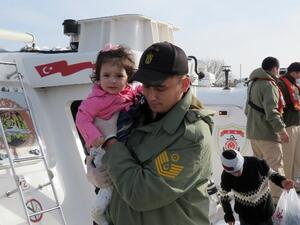 A Turkish Coast guard member holds a child on boat near the village of Kucukkuyu, in western Turkey, on March 8, 2016 after the coast guard arrested a group of migrants and refugees trying to reach the Greek island of Lesbos. (AFP/Stringer)