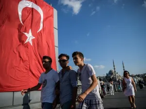 Young people walk on Galata bridge next to a giant Turkish national flag at Eminonu district in Istanbul on July 26, 2016. (Ozan Kose/ AFP)