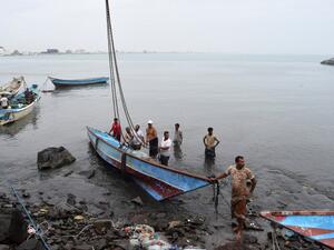 Yemeni men lift a damaged fishing boat out of the water following Cyclone Chapala on November 3, 2015, in the southern port city of Aden. (AFP/Saleh Al-Obeidi)