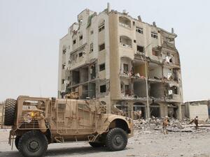 Yemeni fighters loyal to exiled President Abedrabbo Mansour Hadi stand in front of a damaged building in Aden's Khormaksar district on July 15, 2015. (AFP/Saleh al-Obeidi)