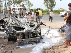 Yemenis inspect a charred vehicle following a suicide car bombing attack that targeted the convoy of Aden's governor, in the southern city of Aden on July 15, 2016. (AFP/Saleh al-Obeidi)