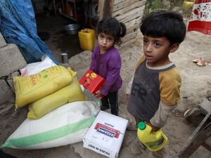 Yemeni children stand next to food rations that a local charity is distributing to families affected by the country's ongoing conflict during the fasting month of Ramadan on June 15, 2016 in an empoverished part of the capital Sanaa. (AFP/Mohammed Huwais)