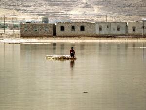A man sits on a rock in a flooded street following heavy rain in the city of Amran, 50 kms north of Yemen's capital Sanaa on April 15, 2016. (AFP/Mohammed Huwais)