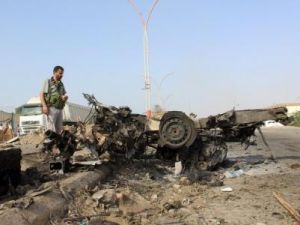 رجل ينظر إلى حطام حافلة في موقع تفجير انتحاري في عدن
