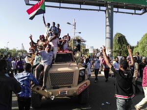 Sudanese protesters wave a national flag (AFP)