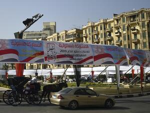 Egyptians pass under banners reading in Arabic "Do what is right", and "Participation is your responsibility", urging voters to participate in the upcoming referendum for the constitutional amendments, in Cairo (AFP)