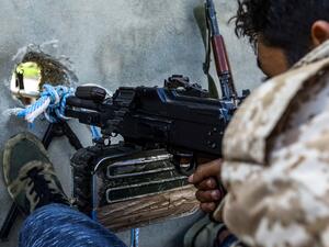 A fighter aims a machine gun through a murder hole at a position held by forces loyal to Libya's Government of National Accord (GNA) in the suburb of Wadi Rabie (AFP)