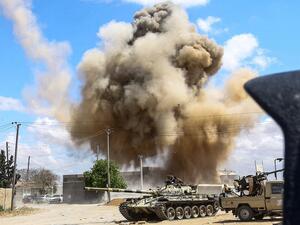 Smoke plume rising from an air strike behind a tank and technicals (pickup trucks mounted with turrets) belonging to forces loyal to Libya's Government of National Accord (GNA), during clashes in the suburb of Wadi Rabie about 30 kilometres south of the capital Tripoli.  Mahmud TURKIA / AFP