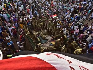 Sudanese demonstrators surround soldiers as they gather near the military headquarters in the capital Khartoum  (AFP)